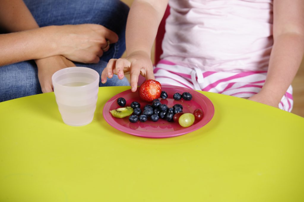 Close-up Of Little Girl Picking Fruit From A Plate